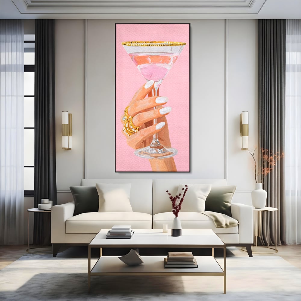 Tablou canvas cu ilustratie cu mana care tine pahar de cocktail, in rama de aluminiu negru, pe perete intr-un living